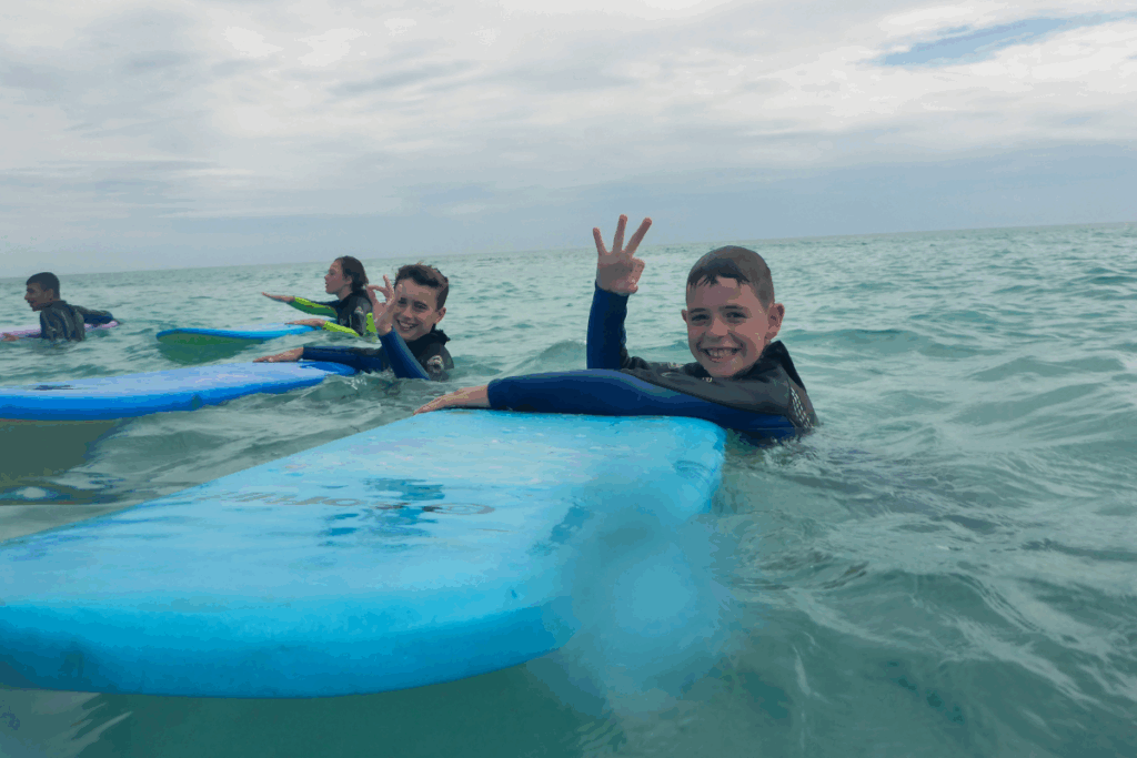 A group of people enjoying the water, with one person holding a surfboard amidst the waves.