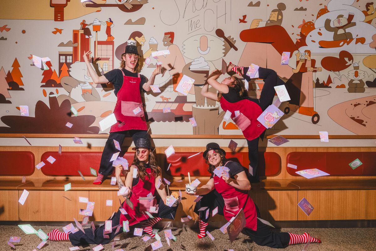 Yo-Chi workers in red aprons joyfully throw colorful confetti into the air, celebrating a festive occasion.