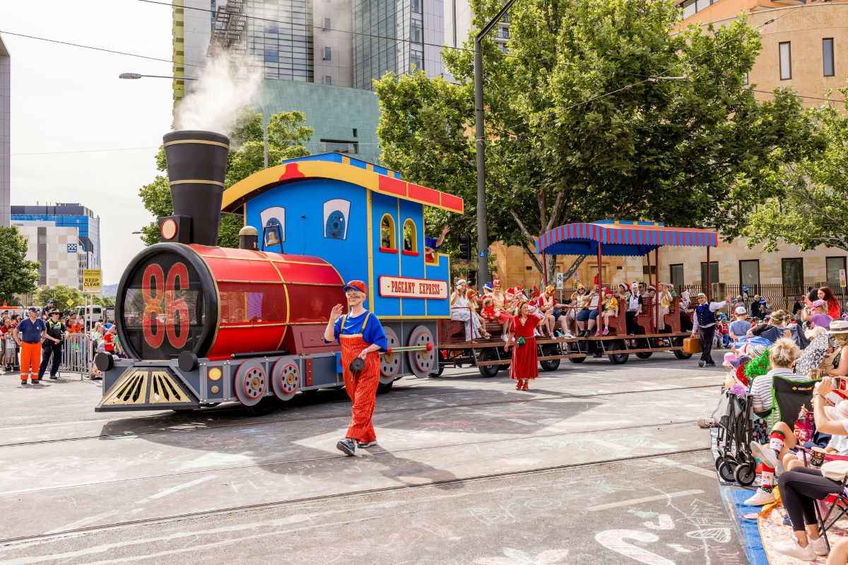  A lively parade featuring a colorful train and crowds of people celebrating in the street.