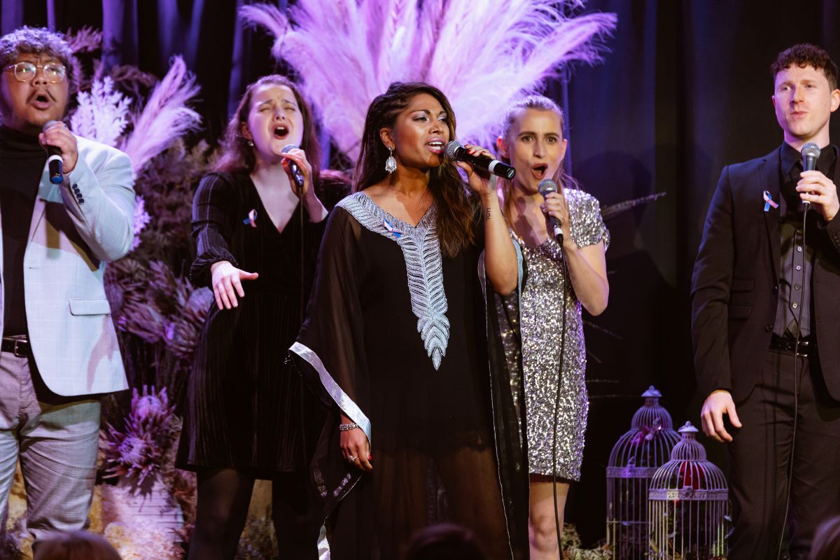  A diverse group of people singing harmoniously together on stage, engaging the audience with their performance.