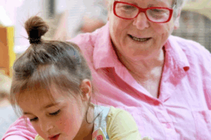 An older woman and a young girl collaborate on a project, sharing ideas and working together at a table.
