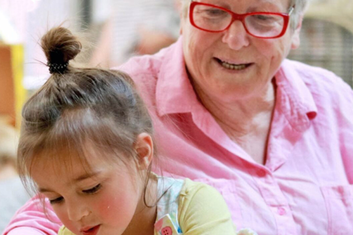 An older woman and a young girl collaborate on a project, sharing ideas and working together at a table.
