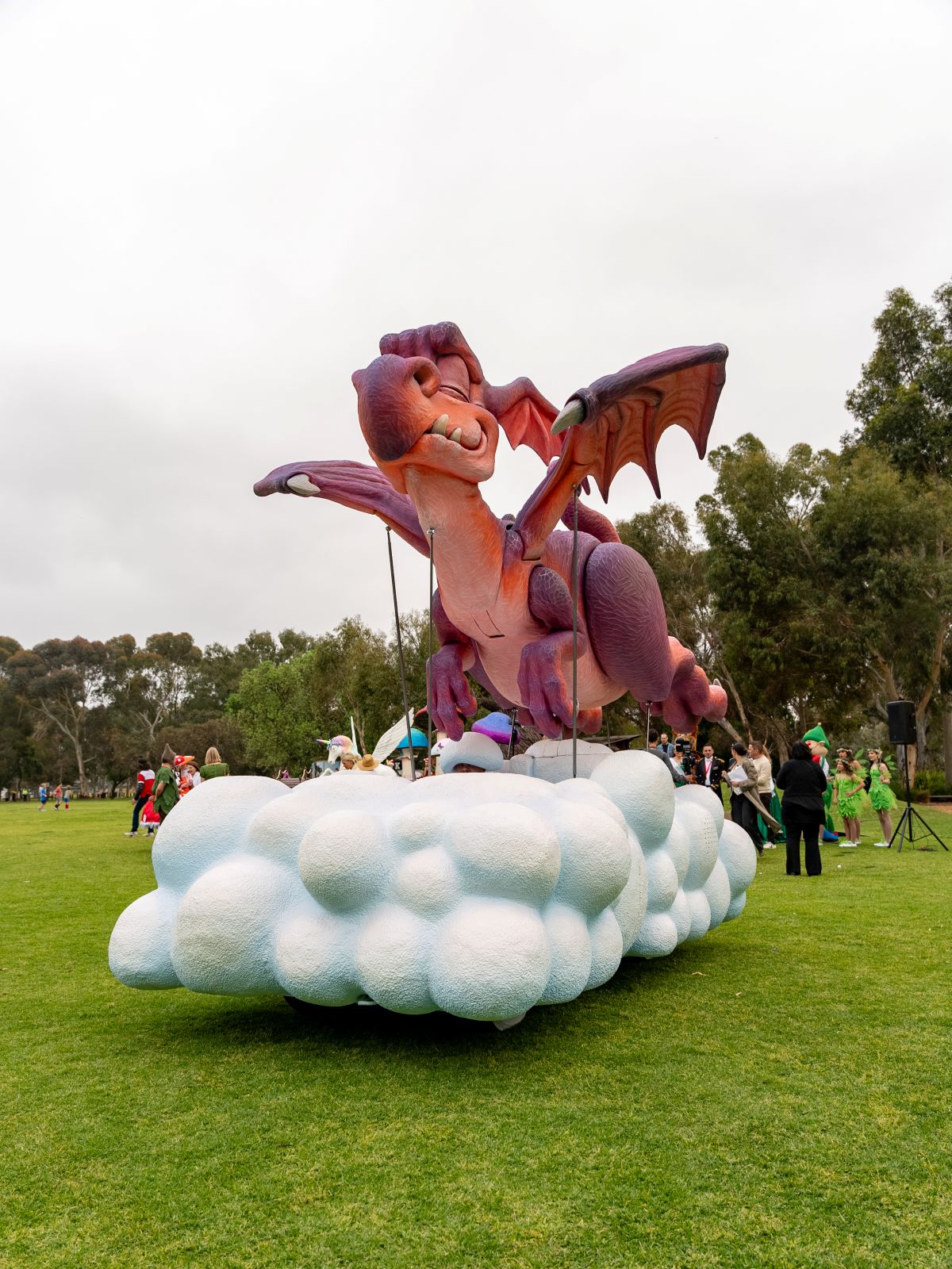A large dragon float positioned in the center of a green field, surrounded by grass and open space.