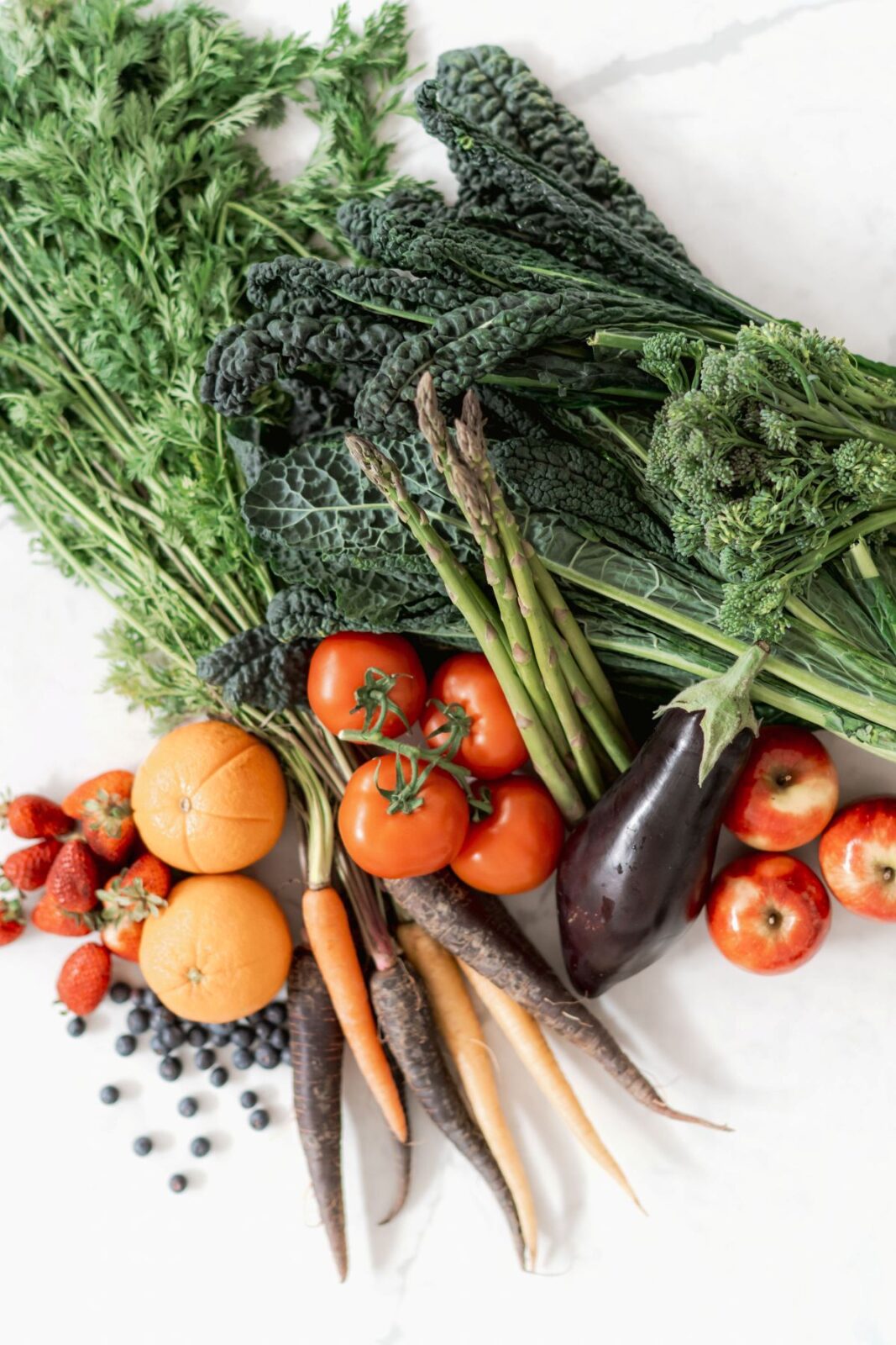 A colorful assortment of vegetables and fruits arranged on a white surface.