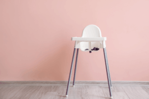 A high chair positioned in front of a vibrant pink wall, creating a cheerful and inviting atmosphere.