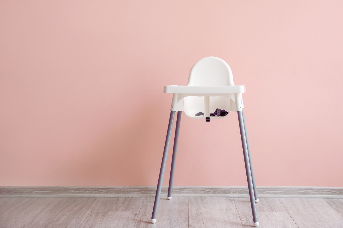 A high chair positioned in front of a vibrant pink wall, creating a cheerful and inviting atmosphere.
