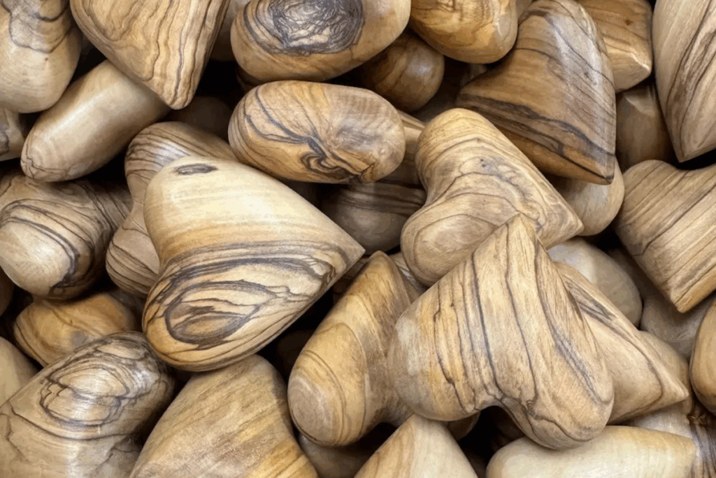 A pile of heart-shaped wooden stones arranged together, showcasing their natural texture and warm tones.