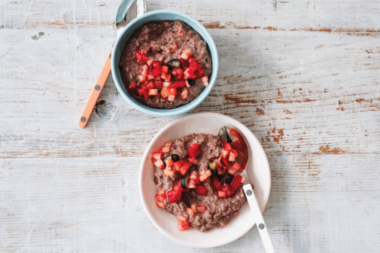 Two bowls of chia pudding topped with fresh strawberries and cherries, arranged on a wooden table.