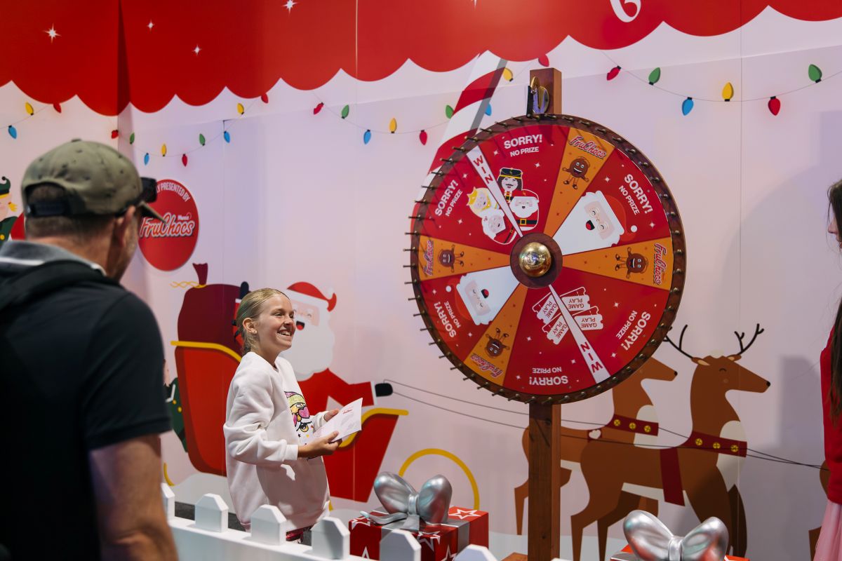 A girl stands beside a spinning wheel