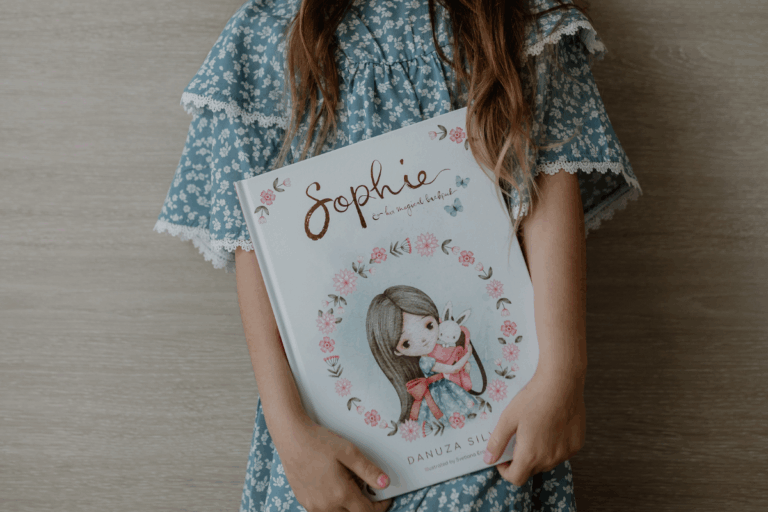 A girl holding the book Sophie's Magical Backpack.