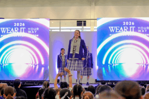 A group of models and designers poses on stage during a vibrant fashion show event.