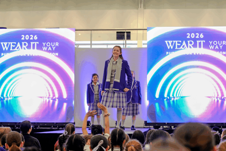 A group of models and designers poses on stage during a vibrant fashion show event.