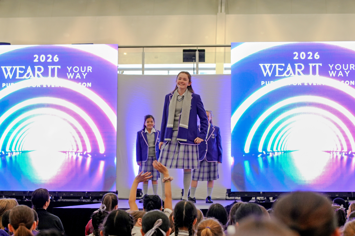 A group of models and designers poses on stage during a vibrant fashion show event.