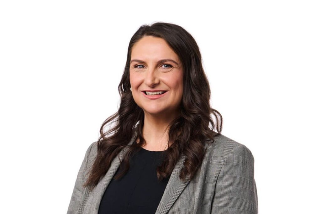 A woman in a tailored suit and black shirt, showcasing a polished and professional appearance.