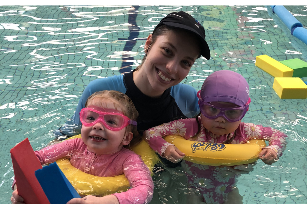 An adult and two children wearing swimming goggles and life jackets, ready for fun in the water.