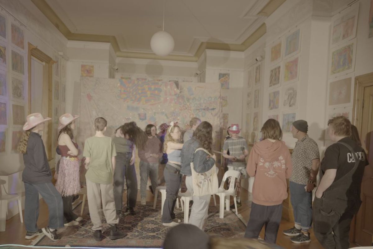 A group of people standing together in a room, engaged in conversation and interacting with one another.