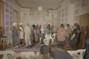 A group of people standing together in a room, engaged in conversation and interacting with one another.