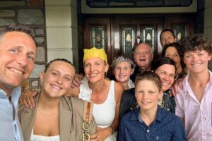 A family gathers for a photo outside their house, capturing a moment of festive joy and unity in a residential setting.