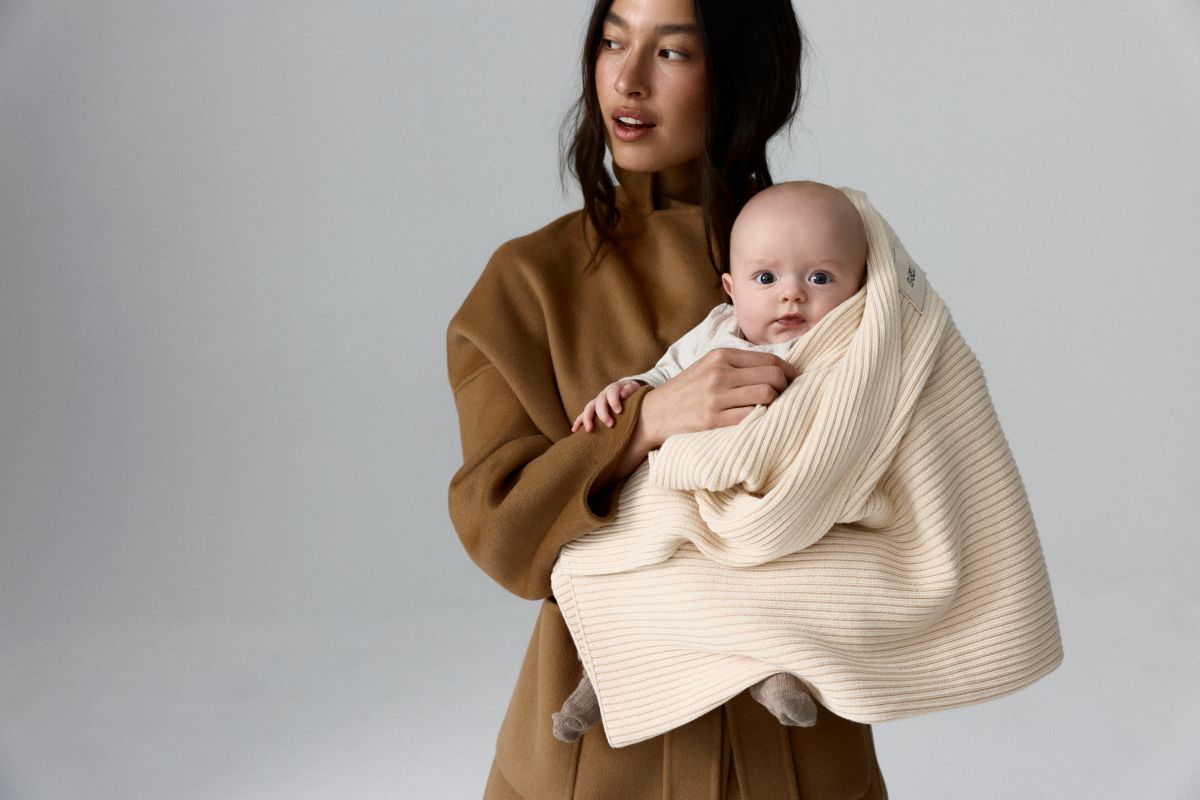 A woman gently cradles a baby wrapped in a soft, knitted blanket, showcasing a tender moment of care and warmth.