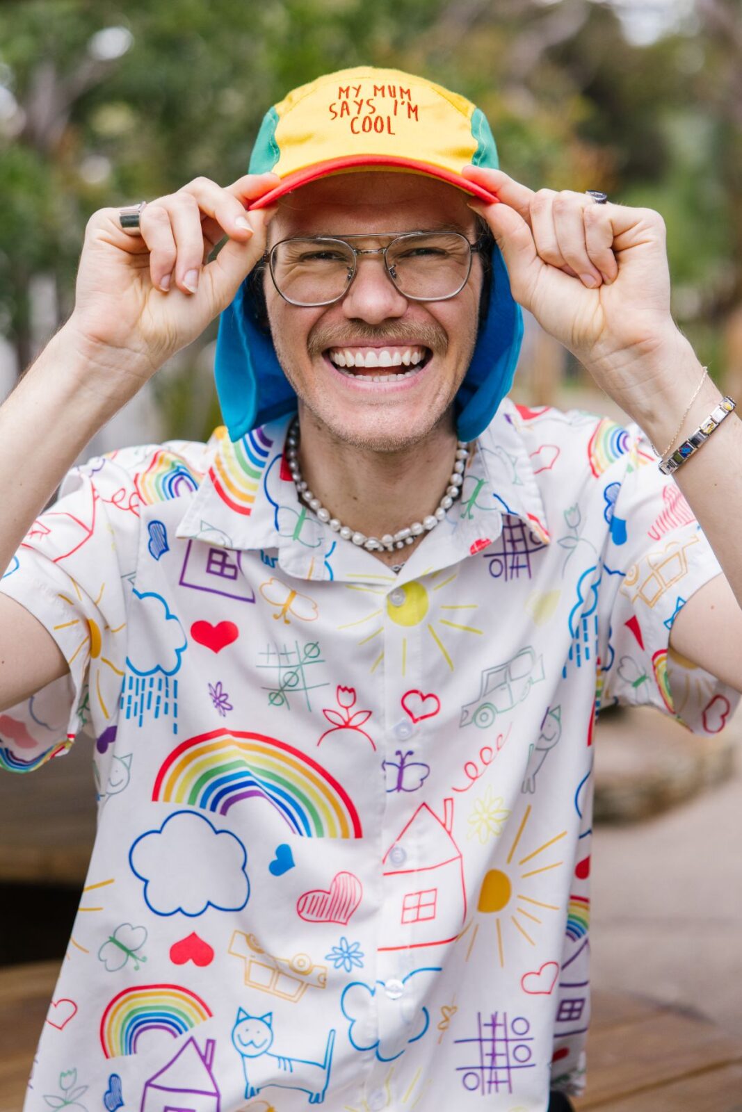 A man wearing a vibrant, patterned shirt and a matching hat, smiling at the camera.