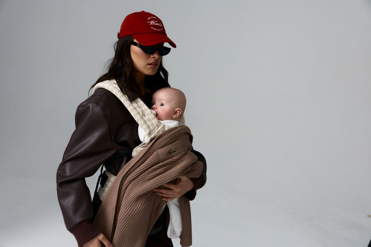 A woman wearing a red hat and jacket is holding a baby in her arms
