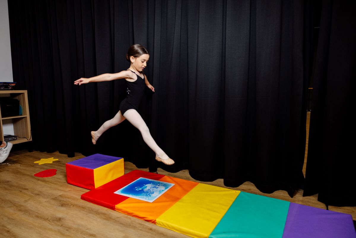 A young girl joyfully jumps on a vibrant, colorful mat, showcasing her playful spirit.