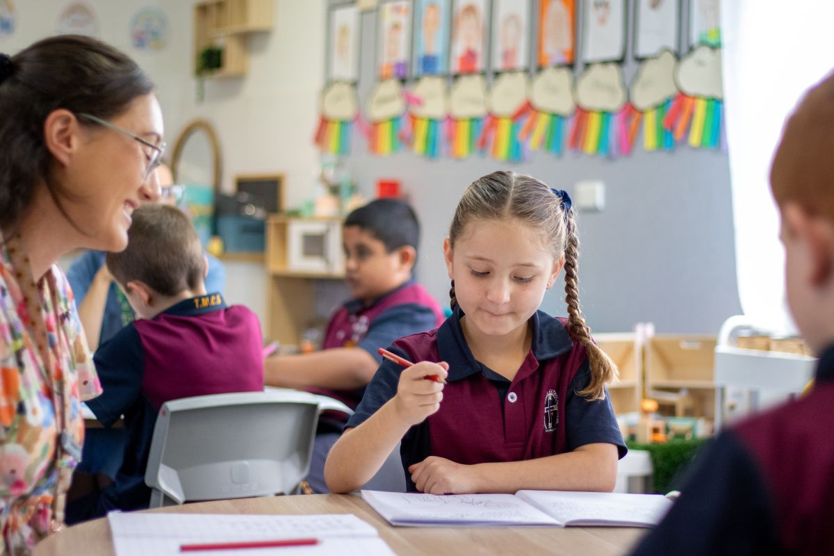 A teacher assists a student with homework in a classroom setting, fostering a supportive learning environment.