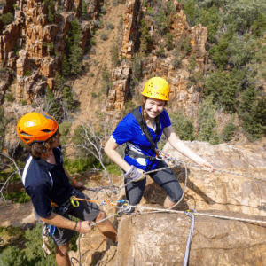 Two people climbing on a rock wall at an outdoor climbing course