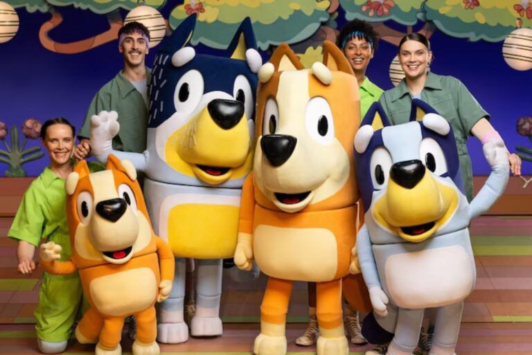 A group of colorful cartoon characters based on the children's show Bluey smiling and posing together for a fun group photo with their puppet masters
