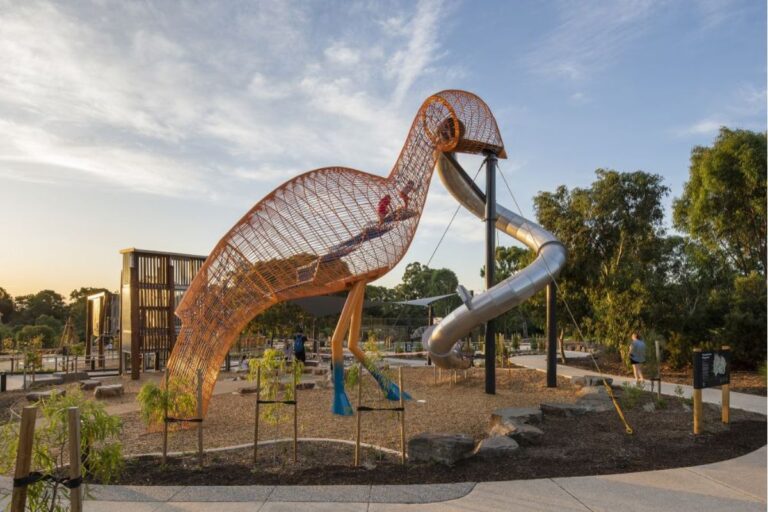 A vibrant playground scene with a tall sculptural slide.