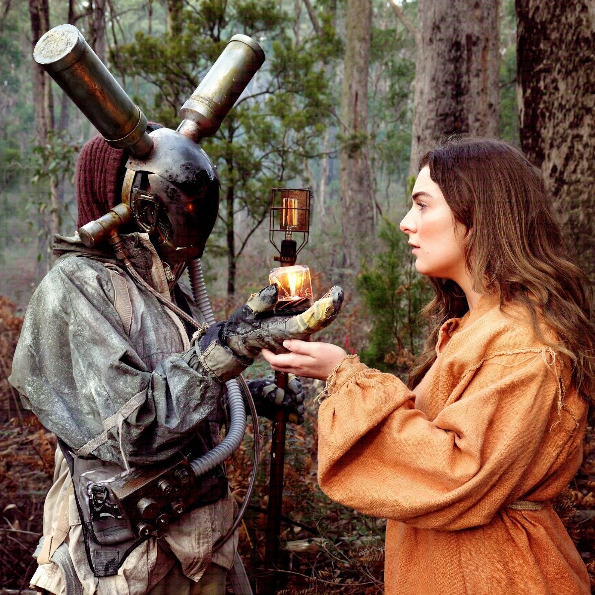 A woman in a costume offers an apple to a man in a costume, both engaged in a playful exchange.