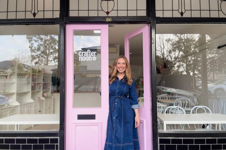 A woman stands confidently in front of a vibrant pink door, showcasing a stylish and inviting entrance.