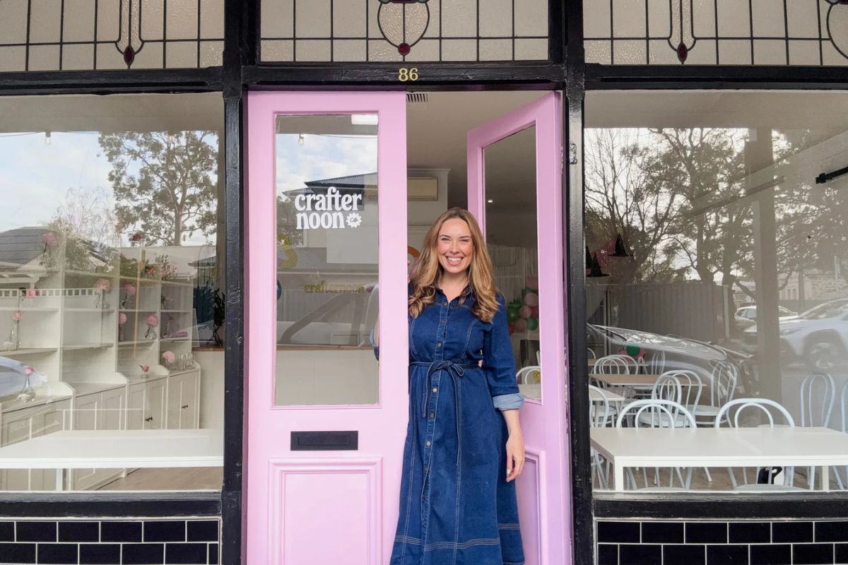 A woman stands confidently in front of a vibrant pink door, showcasing a stylish and inviting entrance.
