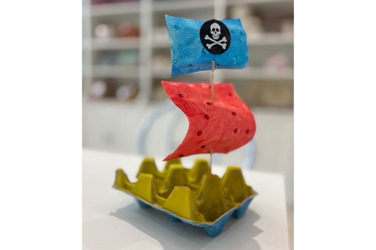 an egg carton fashioned to look like a pirate ship on a table in a craft room
