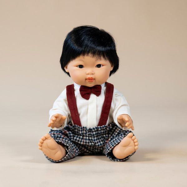 a toy baby boy dressed in a shirt and bowtie sits posing for a portrait photo