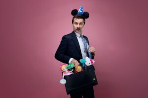 A man dressed in a suit stands with a briefcase full of toys, merging corporate style with a playful element.