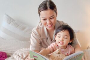 A woman and a child sit together, engrossed in reading a book, sharing a moment of learning and connection.