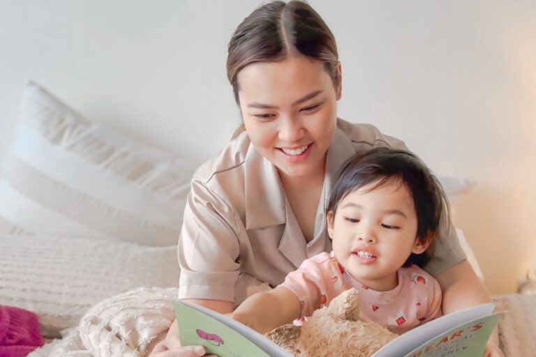 A woman and a child sit together, engrossed in reading a book, sharing a moment of learning and connection.