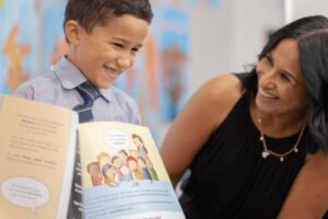 A woman and a boy sit together, engaged in reading a book, sharing a moment of learning and connection.