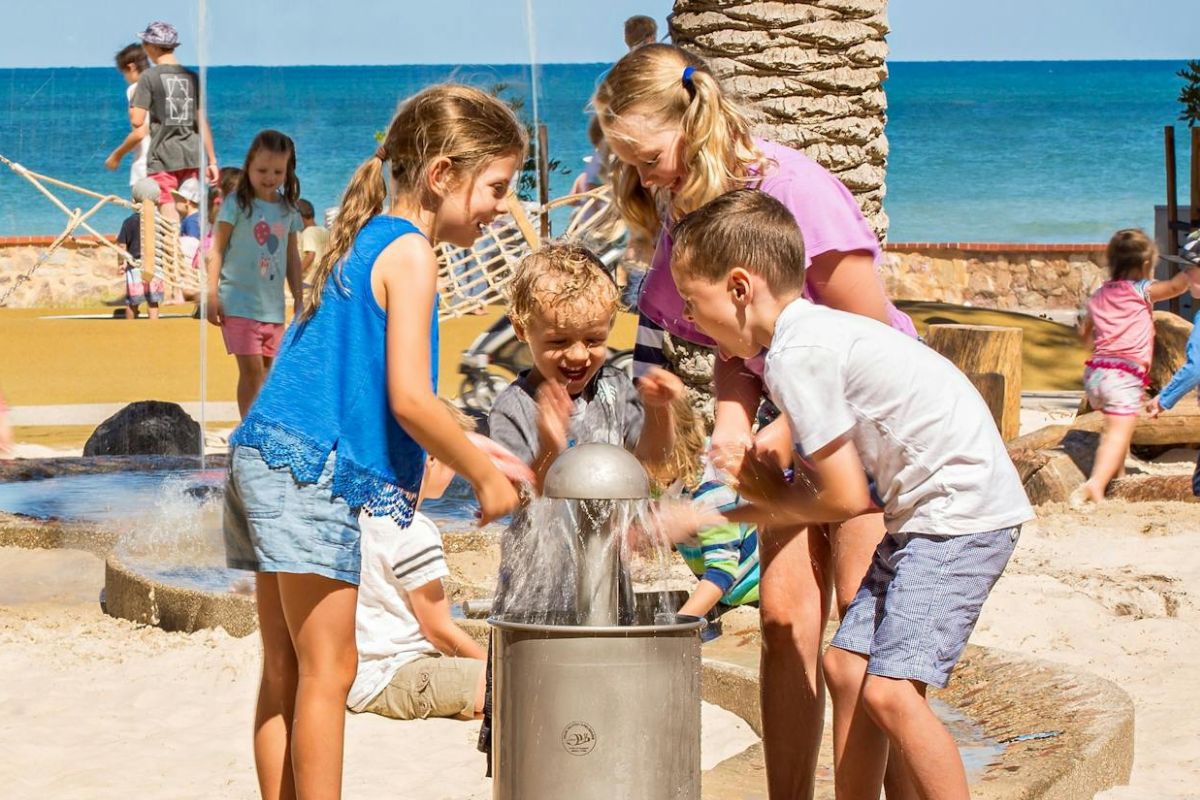 Children joyfully playing in the water at the beach, splashing and enjoying a sunny day by the shore.