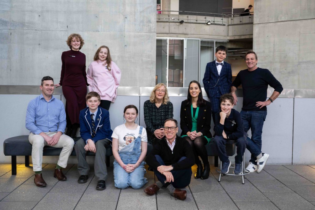 A group of people smiling and posing for a photo in front of a large building.