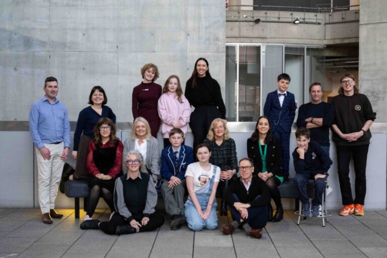 A group of people smiling and posing for a photo in front of a large building.
