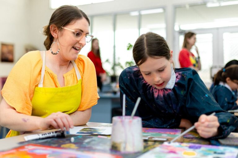 Wilderness school Adelaide student paints in an art class overseen by an art teacher.