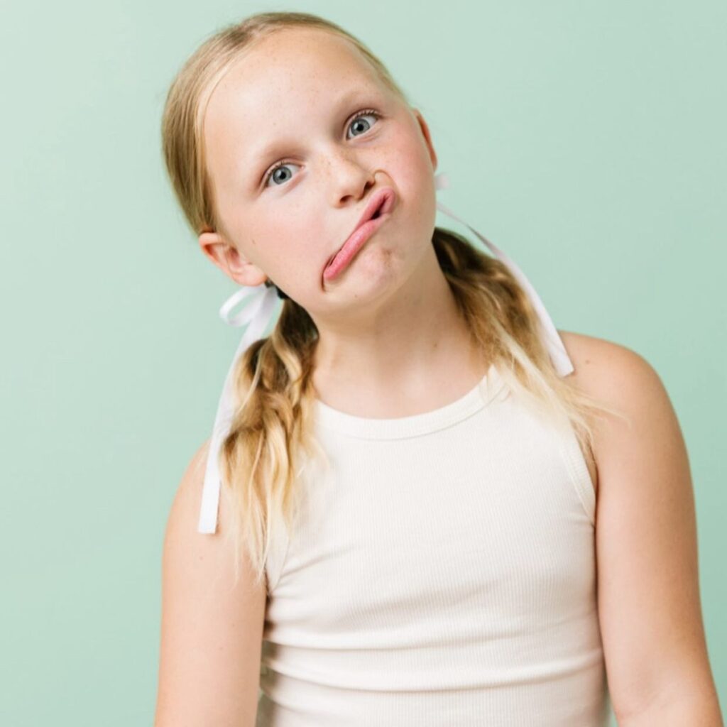 A jovial portrait of a girl in pigtails pulling a funny face.