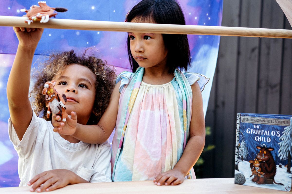 Two children playing with Tara Treasure's toys alongside The Gruffalo childrens book.