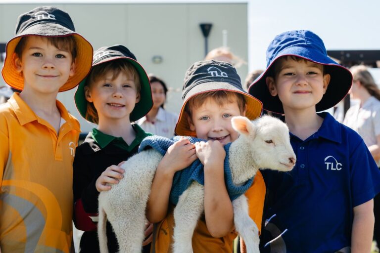 Tatachilla College Adelaide students hold a lamb in the schoolyard.
