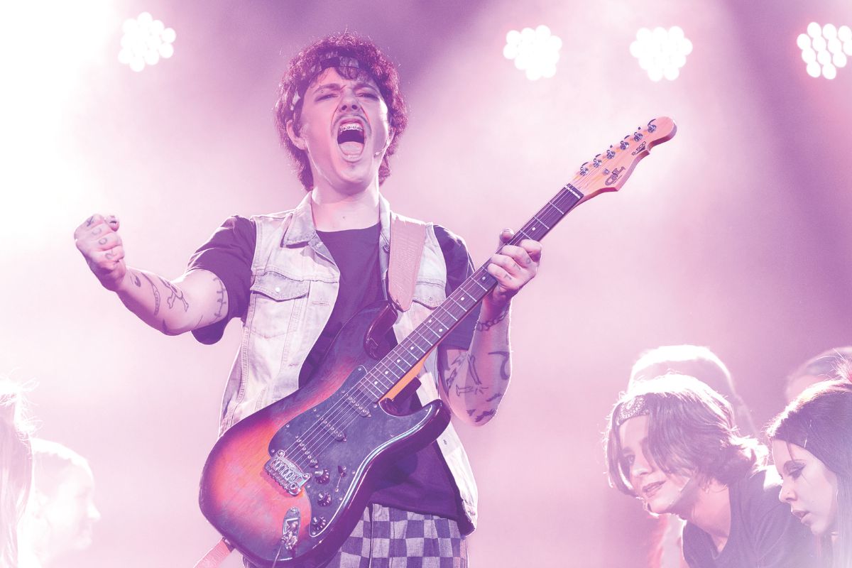 Tatachilla Lutheran College student performs in a musical singing with guitar.