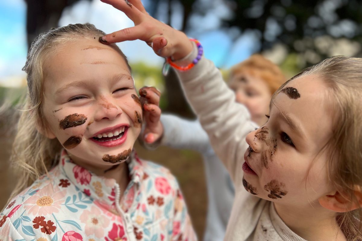 Tatachilla Lutheren College students laugh and play with mud in the school yard. 