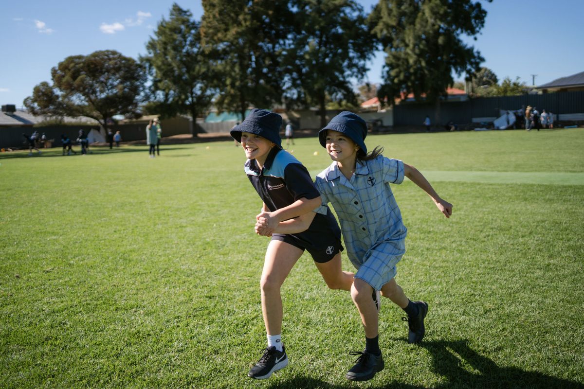 class mates run happily on a school oval.