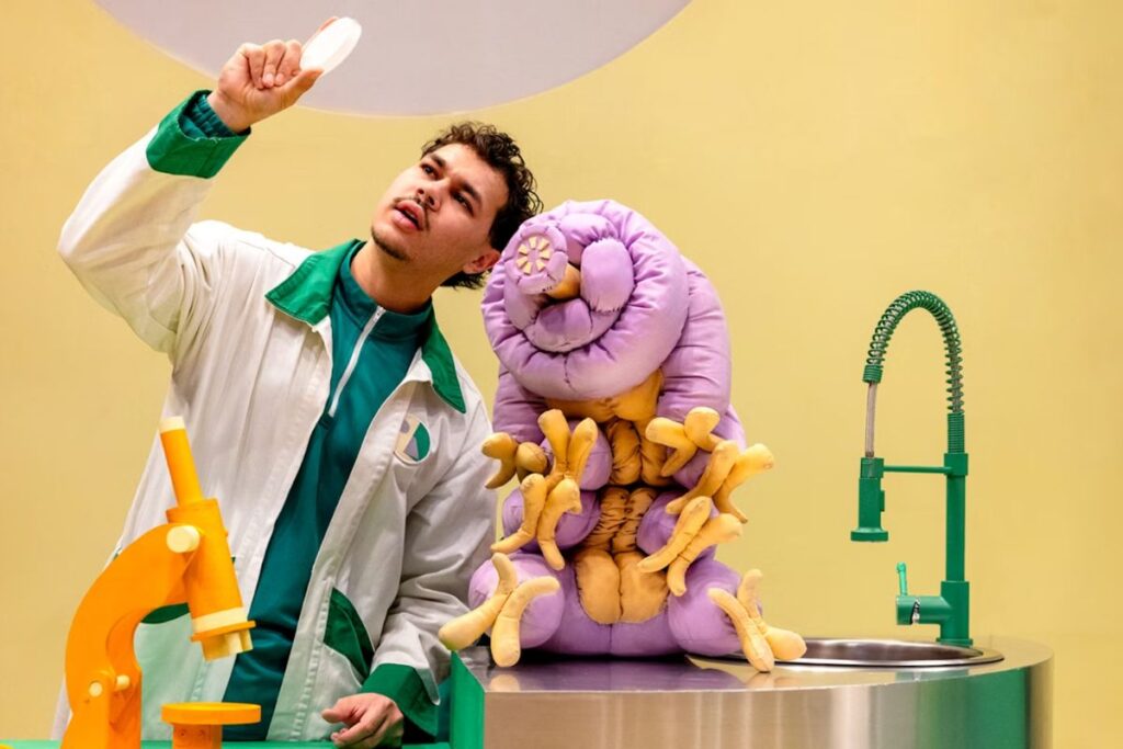 Windmill Theatre production Moss Piglet. character in a lab coat with science laboratory equipment.